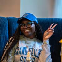 Young woman smiling at camera and giving a peace sign